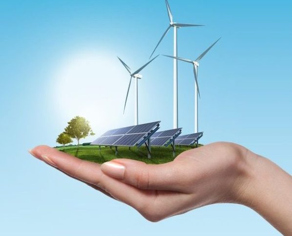 Windturbinen und Sonnenkollektoren auf Wiese mit Baum halten in der Hand der Frau gegen blauen Himmel und Wolken _ Premium Foto